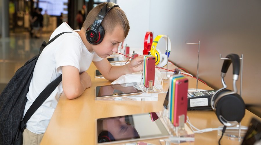 HONG KONG, CHINA - JUNE 18, 2014: The boy with headphones in Apple store in Hong Kong. Store is in a shopping center IFC Mall, it is very popular with locals and tourists visiting Hong Kong.